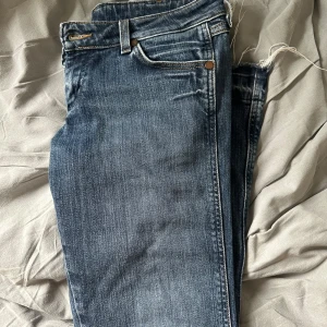 Blå jeans väldigt lågmidjade - Säljer ett par klassiska blå jeans. Har tagit bort sömmen längst ner så att de blivigt längre.