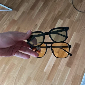 Glasögon  - Två par glasögon perfekt till sommaren! Ena med grönt glas och andra gult med svarta bågar på båda!