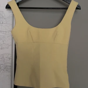 söt topp - Säljer en ljusgul linnetopp från H&M. Toppen har breda axelband och en fyrkantig ringning, perfekt att matcha med jeans eller kjol. Enkel och stilren design som passar till många tillfällen. helt slutsåld på hemsidan🥰 på lappen står det xs men de ör xxs bara att jag använt samma bild 