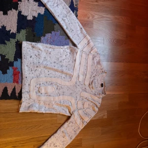 Vit Y2K stickad tröja från Exte - Vintage Y2K stickad tröja från märket Exte. Fin vit tröja med bruna och beiga detaljer samt futuristiska ränder. Finns små blå fläckar på ryggen tack vare fel i tvätten.