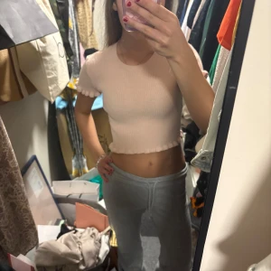 Ljusrosa ribbad croppad topp från Zara - Supersöt ljusrosa croppad topp från Zara med korta ärmar och volangdetaljer vid ärmslut och nederkant. Toppen är ribbad och har en tight passform, perfekt att styla till jeans eller kjol. Skriv för fler bilder och info🥰