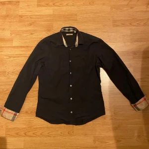 Burberry skjorta - Säljer nu en riktigt fet Burberry skjorta i färgen svart💯 Väldigt bra skick med inga skador💯 Size M💯 Tveka inte att kontakta vid minsta lilla fundering🙏💯