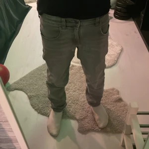 Grå jeans från MNG - Säljer ett par grå jeans från MNG i storlek 152 cm. De har en klassisk femficksdesign med knapp och dragkedja framtill. Perfekta för en stilren look.