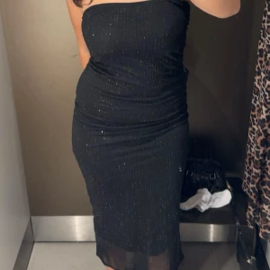 Svart glittrig klänning - Säljer en svart axelbandslös klänning med glittriga detaljer, super fin använd endast en gång🌸