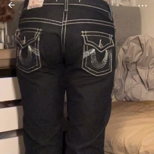 Svarta Ture religion jeans  - Snygga svarta jeans med vita broderier på bakfickorna. De har en bootcut-stil och låg midja. Perfekta för att ge en extra touch till din outfit.
