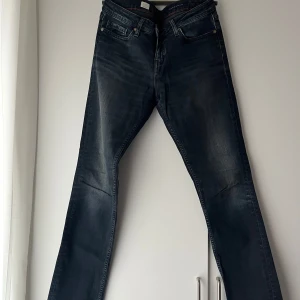 Mörkblå jeans från Tommy Hilfiger - Snygga mörkblå jeans från Tommy Hilfiger med klassisk design och detaljer på bakfickorna. Perfekta för en stilren look. Mid/low-waist, storlek 28/32. 500kr