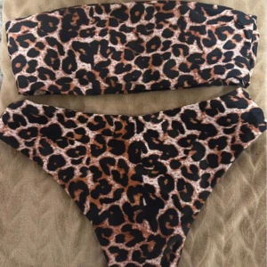 Leopardmönstrad bikini - Trendig bikini med leopardmönster. Överdelen är en bandeau-modell utan axelband och underdelen är en klassisk trosa. Perfekt för en stilren look på stranden.