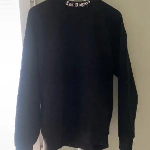 Svart oversized tröja med Los Angeles-tryck - Säljer en svart oversized tröja med stort 'Los Angeles' tryck i vitt på ryggen. Tröjan har långa ärmar och en bekväm passform. Perfekt för en avslappnad stil.