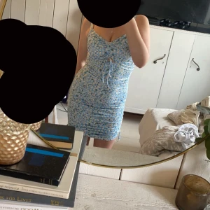 Sommar klänning - Säljer en söt blommig klänning från Shein i ljusblått med vita blommor, den är i ett väldigt stretchigt material och inte genomskinlig. Klänningen har en knytning framtill och smala axelband. Perfekt till sommaren! 🌸