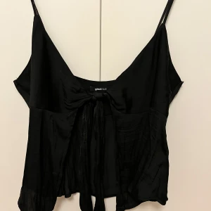 Svart linne från Gina Tricot - Snygg svart linne från Gina Tricot med smala axelband och knytning framtill. Perfekt för en stilren look.