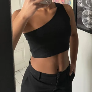 Svart oneshoulder topp - Snygg svart oneshoulder topp i ribbat material 