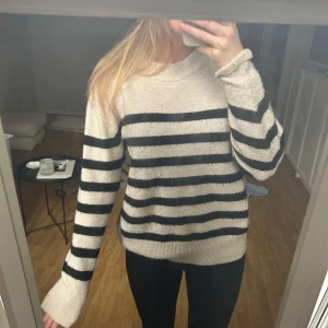 Randig tröja i beige och svart - Säljer en mysig randig tröja i beige och svart. Tröjan har långa ärmar och en rund halsringning. Köpt på H&M 🩵 Bra skick