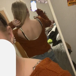 Orange/brun stickad tröja från Gina tricot  - Säljer en snygg orange stickad tröja med ett vågigt mönster. Tröjan har en v-ringad design och långa ärmar, perfekt för höst och vår. Den är både stilren och bekväm, idealisk för att hålla sig varm med stil. Passar bra både bak och fram, går att ha på båda sätten. Den är lite magtröja aktig med ryggen öppnad 