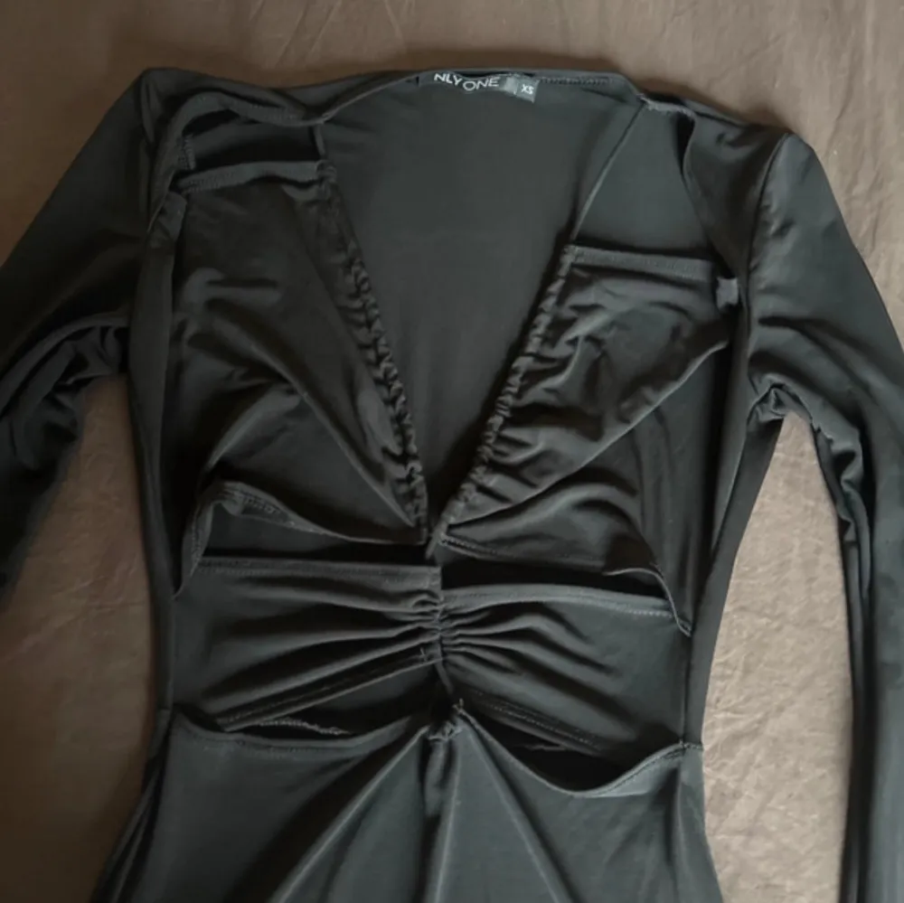 Snygg svart klänning från Nelly i storlek XS. Klänningen har en v-ringad design med rynkade detaljer framtill och långa ärmar. Perfekt för en stilren look.. Mekot.