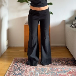 Svarta utsvängda byxor - Snygga lågmidjade vintage kostymbyxor. Midjemåttet är ca 42cm rakt över och innerbenslängden är ca 80cm.