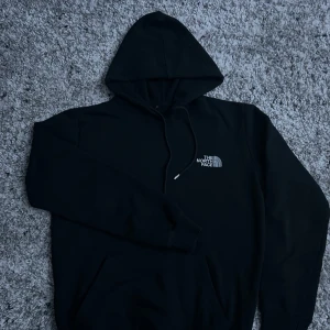 The north face hoodie - Säljer en klassisk svart hoodie från The North Face. Den har en justerbar huva med snören och en broderad logotyp på bröstet. Perfekt för en avslappnad stil. Använd fåtal gånger och passar bra till många outfits