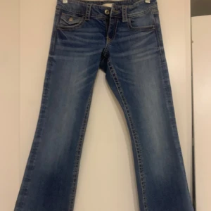 Blå bootcut jeans - Snygga blå bootcut jeans med klassisk femficksdesign och knappgylf. Perfekta för en avslappnad stil. De har en lätt tvättad look som ger en cool vibe. Byxorna är helt nya! 