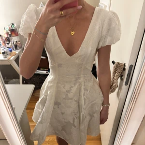 Vit puffig klänning - Säljer denna helt oanvända klänning från Showpo i storlek 34, den har lite glansigt tyg och öppen i ryggen. 