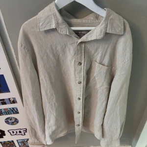Beige linneskjorta från Dressmann - Snygg beige skjorta från Dressmann i linnemix. Klassisk krage, bröstficka och knäppning framtill. Perfekt för dig som gillar en avslappnad men stilren look. Långärmad och i luftig, skön kvalitet.