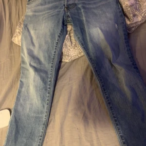 Blå jeans från Dsquared2, 16Y - Säljer ett par snygga blå jeans från Dsquared2 i storlek 16Y. Jeansen har klassisk femficksdesign, normal passform och är tillverkade i slitstarkt denim. De har en ljus tvätt och Dsquared2-logga vid gylfen. Perfekta för dig som gillar streetstyle.