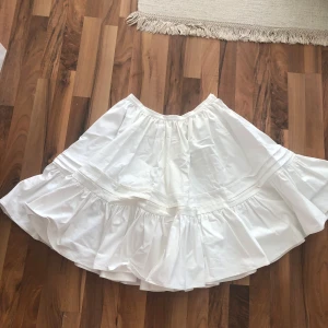 Vit volangkjol i bomull - Superfin vit kjol med volanger, rynkade detaljer och stråveck. Kjolen är i bomull och har en luftig, flowy känsla. Perfekt för dig som gillar en romantisk och avslappnad stil. Stängs med knapp i midjan❣️