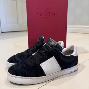 Valentino flycrews - Mörkblåa sneakers från Valentino Garavani med klassisk siluett. Ovandel i mörkblå mocka och vitt skinn, vita detaljer och sula med små nitar. Tunga med guldfärgad logotyp. Snygga och stilrena skor som lyfter din outfit. Super fint skick på dem. Storlek 40. Hör av dig om minsta fundering. Jag tar även imot byten.
