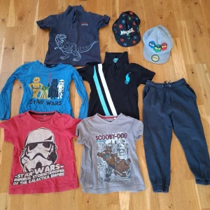 Klädpaket, 110-116, byxor 120 bl. Polo Ralph Lauren pikétröja - Svart pikétröja från Polo Ralph Lauren med turkos logga på bröstet och två diagonala ränder i turkos och vitt. Klassisk krage och kort ärm, perfekt för en sportig och cool look. Materialet känns som bomull. Klädpaket, star wars, Ralph Lauren, paket, pojke 110-116 Strl 110-116 Byxor: 120 