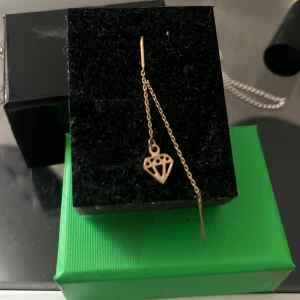 Guldigt örhänge med diamantform - Snyggt guldigt örhänge från L8H med tunn kedja och en cool diamantformad hängande detalj. Perfekt för dig som gillar minimalistiska smycken med en twist. Lätt att trä igenom örat för en trendig look.