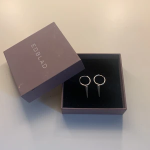 Silvriga örhängen med spike från Edblad - Snygga silvriga örhängen från Edblad med coola spike-detaljer. Runda hoops med spetsig hängande kon ger en edgy vibe. Perfekta för dig som vill sticka ut med en stilren men tuff accessoar. Nypris 399kr mitt pris 240kr jag är öppen för bud