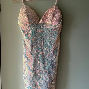 Glittrig rosa paljettklänning Fashion Nova - Supersnygg kort klänning från Fashion Nova i ljusrosa med massor av glittriga paljetter. Figurnära modell med smala axelband och djup urringning. Perfekt för dig som vill sticka ut och glänsa på nästa event!