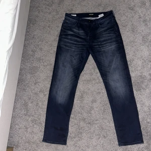 Mörkblå jeans från Jack & Jones, 30/30 - Snygga mörkblå jeans från Jack & Jones i storlek 30/30. Jeansen har lite snygga slitningar. Dom är knappt använda och är därför i mycket bra skick.