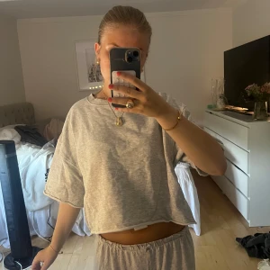 Grå croppad tröja från Zara - Grå croppad tröja från Zara med loose fit och korta ärmar. Tröjan har rund halsringning och är gjord i mjuk bomull. Köpte för ca ett år sen andvänd få gånger. Nypriset är 179.