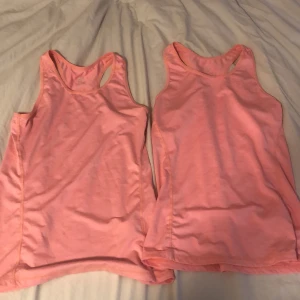 2 rosa linnetoppar från H&M - Två stycken ljusrosa linnetoppar från H&M med klassisk racerback och rund halsringning. Perfekta för träning eller chill dagar. Tillverkade i mjuk bomullsmix som andas och sitter skönt mot kroppen.