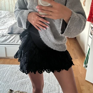 Svart volangkjol med broderade detaljer - Supersöt svart kortkjol med flera lager volanger och broderade detaljer. Kjolen har en tight passform upptill och voluminös nederdel, perfekt för att sticka ut. Stängs med dragkedja på sidan! Säljer då jag köpt en större storlek ❤️💞