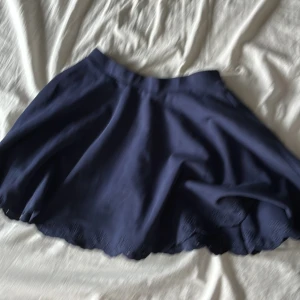 Mörkblå kjol från Polo Ralph Lauren - Supersöt mörkblå kortkjol från Polo Ralph Lauren med broderade detaljer längst ner. Kjolen har en lätt utsvängd form och är perfekt för dig som gillar en klassisk men ändå lekfull stil. Passar till både sneakers och boots.