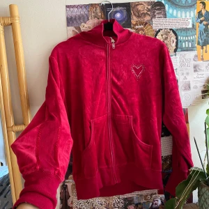 Röd velour set med hjärtdetalj Lindex - Mysig röd velourjacka från Lindex med dragkedja framtill, två stora fickor och ribbade muddar. På bröstet finns en söt hjärtdetalj i små stenar. Perfekt för chill dagar och snygg att matcha med mjukisbyxor. Passar mig med storlek 40!