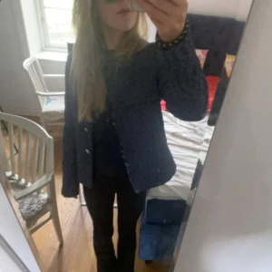 Blå tweed kavaj från Morris - Snygg blåmelerad kavaj från Morris i klassisk tweed. Rak passform med rundad halsringning, dekorativa knappar framtill och två fickor. Perfekt för dig som gillar en stilren och tidlös look. Fodrad insida för extra komfort.                            Jag har tagit bort dom guldiga knapparna men dom kan man få med om de är så att de önskas!