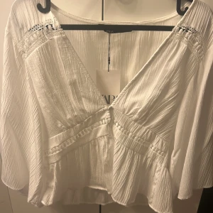 Vit från Zara - Superfin somrig vit omlottblus från Zara med v-ringning. Helt oanvänd med prislapp på!