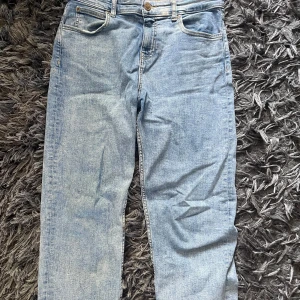 Ljusblå Lee jeans straight fit - Säljer ett par klassiska ljusblå jeans från Lee i rak modell. har gylf med dragkedja och knapp samt snygga kontrastsömmar. Perfekta för dig som gillar en enkel och tidlös look. 