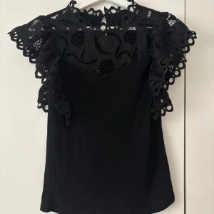 Svart spetsblus  - Säljer en svart spetsblus som är helt oanvänd, endast testad! 😇 Blusen har en spetskrage tillsammans med volanger vid ärmarna 🥰Skulle säga att den är mindre i storlek!