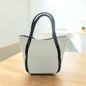 Perllini Tvåfärgad Tote - Stilren & strukturerad tote i krämvitt och svart från Perllini. Präglat veganskt läder med kontrasterande handtag och detaljer. Rymligt innerfoder med logotyp, dragkedjeficka + 2 öppna fack. Stängs med magnetknapp.  👜 Snygg. Minimalistisk. Praktisk. Perfekt för jobb, skola eller vardagsslay.