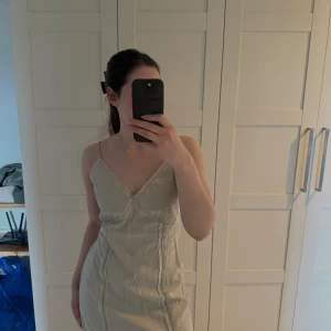 Ljusgrön långklänning med smala axelband - Säljer en långklänning med smala axelband och djup öppen rygg. Klänningen har v-ringad front och söta sömdetaljer längs sidorna. Perfekt för varma dagar och somriga vibes.