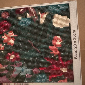 Diamond painting med blommotiv  - Säljer en kvadratisk diamond painting med färgglatt blommotiv. Tavlan är 20x20 cm och består av små pärlor i nyanser av rött, rosa, blått, grönt och vitt. 