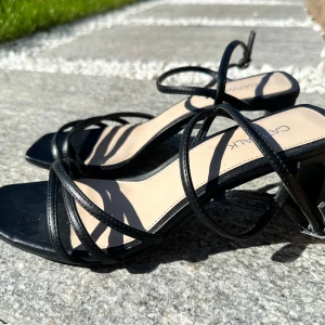 Svarta sandaler med klack  - Säljer ett par svarta sandaler från med smala remmar och fyrkantig tå. Skorna har en medelhög klack och öppen tå, perfekta för varma dagar. Stilren design som passar till många outfits.😍nyskick! 