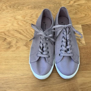 Ljuslila sneakers från Race Marine - Säljer ett par ljuslila sneakers från Race Marine med klassisk design. Skorna har snörning framtill, vit platt sula och rund tå. Perfekta för dig som gillar stilrena och bekväma skor till vardags. Priset går att diskutera.