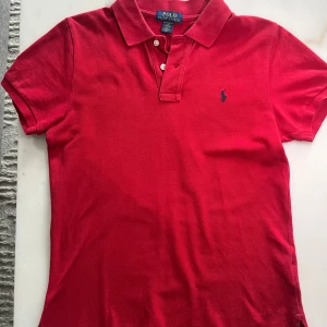 Polo Ralph Lauren Röd Tröja - Säljer en stilren och klassisk röd tröja från Polo Ralph Lauren i storlek S. Den har en tidlös design med diskret broderad logga på bröstet och passar perfekt både till vardags och en mer avslappnad stil. Tröjan är i fint skick och priset kan diskuteras vid seriöst intresse.