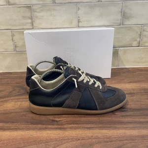Maison Margiela GATS - Maison Margiela GATS | Skicket är 8.5/10 - Storlek 44 - Nypris 5999kr - Vårat pris 3399 - Skorna är i jättefint skick och de har i princip inga defekter, endast lite vid ena tån men märks inte alls. Allt og följer med (box,skopåsar). Tveka inte vid att ställa frågor vid funderingar!