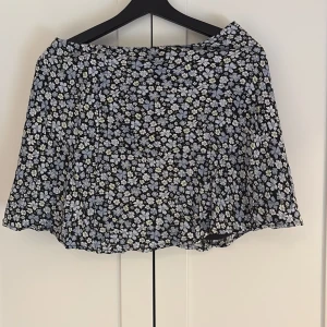 Blommig kortkjol från H&M Divided - Supersöt svart kortkjol med små vita och ljusblå blommor från H&M Divided. Kjolen har en lätt utsvängd form och är perfekt för varma dagar. Tunn och luftig med mjukt tyg som ger en skön känsla. Här av dig till mig vid intresse!💕