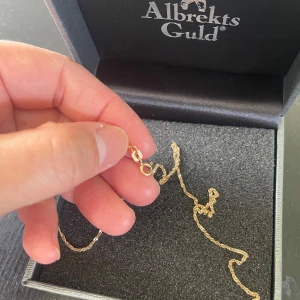 Guldfärgat armband från Albrekts Guld - Säljer ett tunt och elegant halsband i guldfärg från Albrekts Guld. Kedjan är finlänkad och smidig, perfekt för dig som gillar stilrena smycken. Levereras i originalask. Stämpel 750 Singapore kedja.