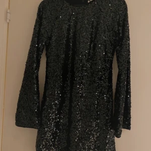 Svart paljettklänning med lång ärm - Säljer en tight svart glittrig paljettklänning från H&M med långa ärmar, aldrig använd 